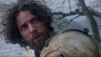 Movie still from “Excalibur” (1981), directed by John Boorman – A person with a beard wearing armor; Close Up shot, Low angle