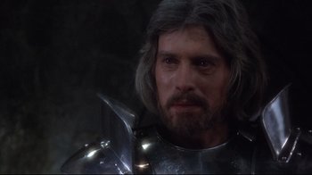 Movie still from “Excalibur” (1981), directed by John Boorman – A person wearing a suit of armor; Close Up shot, Over the shoulder angle