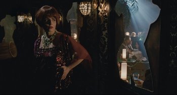 Movie still from “Exotica” (1994), directed by Atom Egoyan – A woman standing in front of a mirror in a dark room; Medium shot, Over the shoulder angle