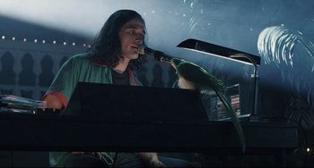 Movie still from “Exotica” (1994), directed by Atom Egoyan – A man holding a pipe in front of a green parrot; Medium shot, Low angle