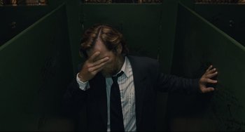 Movie still from “Exotica” (1994), directed by Atom Egoyan – A man in a suit and tie covering his face with his hands; Close Up shot, Low angle