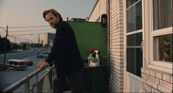 Movie still from “Exotica” (1994), directed by Atom Egoyan – A man standing on a balcony next to a potted plant; Medium shot, Low angle