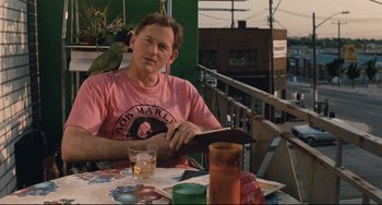 Movie still from “Exotica” (1994), directed by Atom Egoyan – A man sitting at an outdoor table with a parrot on his lap; Medium shot, Over the shoulder angle