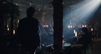 Movie still from “Exotica” (1994), directed by Atom Egoyan – A man standing in a dark room with a microphone; Wide shot, Over the shoulder angle