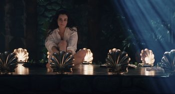 Movie still from “Exotica” (1994), directed by Atom Egoyan – A woman sitting on the ground in front of a plant; Medium shot, High angle