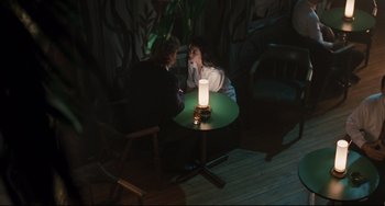 Movie still from “Exotica” (1994), directed by Atom Egoyan – Two people sitting at a table with a candle in the middle of the room; Wide shot, High angle