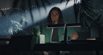 Movie still from “Exotica” (1994), directed by Atom Egoyan – A man sitting at a keyboard in front of a microphone; Medium shot, Over the shoulder angle