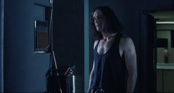 Movie still from “Exotica” (1994), directed by Atom Egoyan – A man with long black hair standing in front of a mirror; Medium shot, Over the shoulder angle