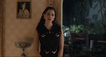 Movie still from “Exotica” (1994), directed by Atom Egoyan – A woman in a black dress standing next to a mirror; Medium shot, Over the shoulder angle