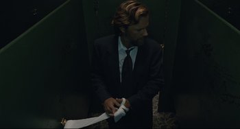 Movie still from “Exotica” (1994), directed by Atom Egoyan – A man in a suit and tie holding a white ribbon; Medium shot, Low angle