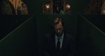 Movie still from “Exotica” (1994), directed by Atom Egoyan – A man in a suit and tie sitting in a room; Medium shot, Low angle