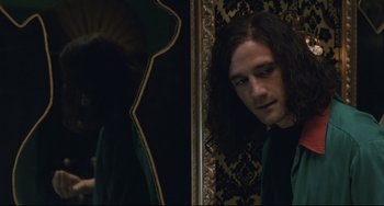 Movie still from “Exotica” (1994), directed by Atom Egoyan – A man with long hair looking at himself in a mirror; Medium shot, Over the shoulder angle