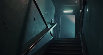 Movie still from “Exotica” (1994), directed by Atom Egoyan – A view of some stairs in a dark room; Wide shot, Low angle