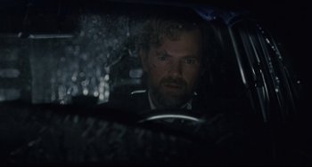 Movie still from “Exotica” (1994), directed by Atom Egoyan – A man sitting in the driver's seat of a car in the rain; Close Up shot, Over the shoulder angle
