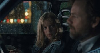 Movie still from “Exotica” (1994), directed by Atom Egoyan – A woman sitting in the back seat of a car next to a man; Close Up shot, Over the shoulder angle