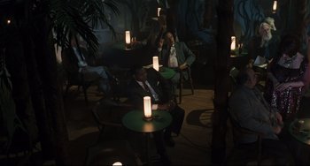 Movie still from “Exotica” (1994), directed by Atom Egoyan – A group of people sitting at a table in a dark room; Wide shot, High angle