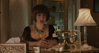 Movie still from “Exotica” (1994), directed by Atom Egoyan – A woman sitting at a table in front of a phone; Medium shot, Over the shoulder angle