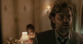 Movie still from “Exotica” (1994), directed by Atom Egoyan – A man in a suit sitting in front of a woman in a chair; Close Up shot, Over the shoulder angle