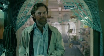 Movie still from “Exotica” (1994), directed by Atom Egoyan – A man with a beard is standing under an umbrella; Medium shot, Low angle