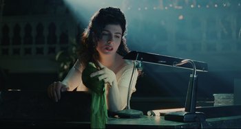 Movie still from “Exotica” (1994), directed by Atom Egoyan – A woman sitting at a table holding a green cloth; Medium shot, Low angle