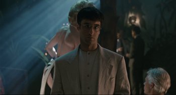 Movie still from “Exotica” (1994), directed by Atom Egoyan – A man wearing a suit and glasses standing next to a woman in a dress; Close Up shot, Over the shoulder angle