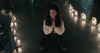 Movie still from “Exotica” (1994), directed by Atom Egoyan – A woman sitting on the ground with her legs crossed; Medium shot, High angle