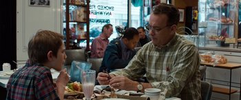 Movie still from “Extremely Loud & Incredibly Close” (2011), directed by Stephen Daldry – A group of people sitting at a table with food and drinks; Medium shot, Over the shoulder angle
