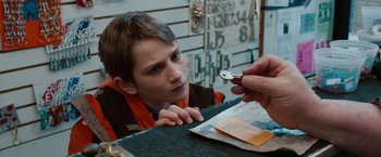 Movie still from “Extremely Loud & Incredibly Close” (2011), directed by Stephen Daldry – A young boy sitting at a table with a key in his hand; Close Up shot, High angle