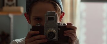 Movie still from “Extremely Loud & Incredibly Close” (2011), directed by Stephen Daldry – A young boy taking a picture with a camera; Close Up shot, Low angle
