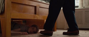 Movie still from “Extremely Loud & Incredibly Close” (2011), directed by Stephen Daldry – A child laying on the floor next to an adult's foot; Medium shot, High angle