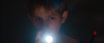 Movie still from “Extremely Loud & Incredibly Close” (2011), directed by Stephen Daldry – A young boy holding a flashlight up to his face; Close Up shot, Low angle