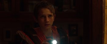 Movie still from “Extremely Loud & Incredibly Close” (2011), directed by Stephen Daldry – A young boy holding a flashlight in a dark room; Close Up shot, Over the shoulder angle