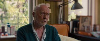 Movie still from “Extremely Loud & Incredibly Close” (2011), directed by Stephen Daldry – An older man sitting in a chair looking at the camera; Close Up shot, Over the shoulder angle