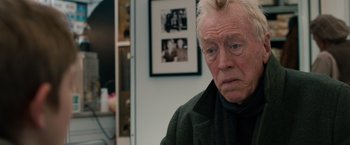 Movie still from “Extremely Loud & Incredibly Close” (2011), directed by Stephen Daldry – An older man with a mohawk haircut stares into the camera; Close Up shot, Over the shoulder angle