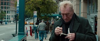 Movie still from “Extremely Loud & Incredibly Close” (2011), directed by Stephen Daldry – An older man smoking a cigarette on the sidewalk; Close Up shot, Over the shoulder angle
