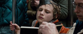 Movie still from “Extremely Loud & Incredibly Close” (2011), directed by Stephen Daldry – A young man wearing a helmet and holding a book in his hands; Close Up shot, Over the shoulder angle