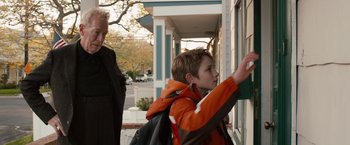 Movie still from “Extremely Loud & Incredibly Close” (2011), directed by Stephen Daldry – A young boy in an orange jacket is looking out a window; Medium shot, Over the shoulder angle