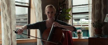 Movie still from “Extremely Loud & Incredibly Close” (2011), directed by Stephen Daldry – A woman holding a cello in front of a window; Medium shot, Low angle