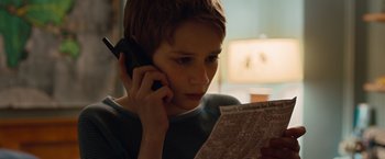 Movie still from “Extremely Loud & Incredibly Close” (2011), directed by Stephen Daldry – A young boy holding a newspaper and talking on a phone; Close Up shot, High angle