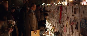 Movie still from “Extremely Loud & Incredibly Close” (2011), directed by Stephen Daldry – A group of people standing around a wall of candles; Medium shot, Over the shoulder angle