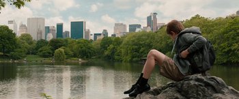 Movie still from “Extremely Loud & Incredibly Close” (2011), directed by Stephen Daldry – A person sitting on a rock near a body of water; Wide shot, Over the shoulder angle
