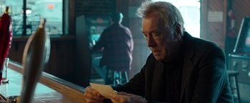 Movie still from “Extremely Loud & Incredibly Close” (2011), directed by Stephen Daldry – An older man sitting at a table looking down at a piece of paper; Close Up shot, Over the shoulder angle