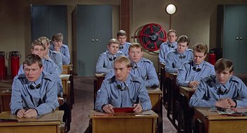 Movie still from “Fahrenheit 451” (1966), directed by François Truffaut – A group of men sitting at desks in a classroom; Medium shot, High angle