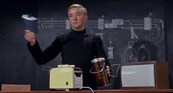 Movie still from “Fahrenheit 451” (1966), directed by François Truffaut – A man holding a coffee mug in front of a chalkboard; Medium shot, Low angle