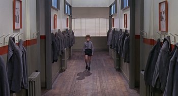 Movie still from “Fahrenheit 451” (1966), directed by François Truffaut – A young boy is standing in a hallway of uniforms; Wide shot, High angle