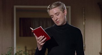 Movie still from “Fahrenheit 451” (1966), directed by François Truffaut – A man in a black shirt is reading a red book; Close Up shot, Low angle