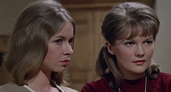 Movie still from “Fahrenheit 451” (1966), directed by François Truffaut – Two young women sitting next to each other in front of a wooden wall; Close Up shot, High angle