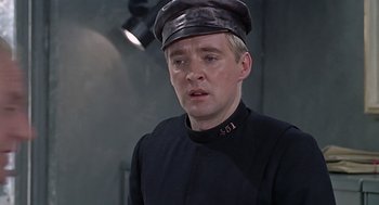 Movie still from “Fahrenheit 451” (1966), directed by François Truffaut – A man wearing a black uniform and a black hat; Close Up shot, Over the shoulder angle