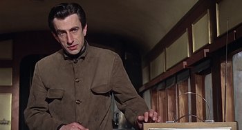 Movie still from “Fahrenheit 451” (1966), directed by François Truffaut – A man standing in a kitchen holding a knife; Medium shot, Low angle