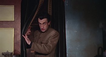 Movie still from “Fahrenheit 451” (1966), directed by François Truffaut – A man standing in front of a curtain; Medium shot, Low angle